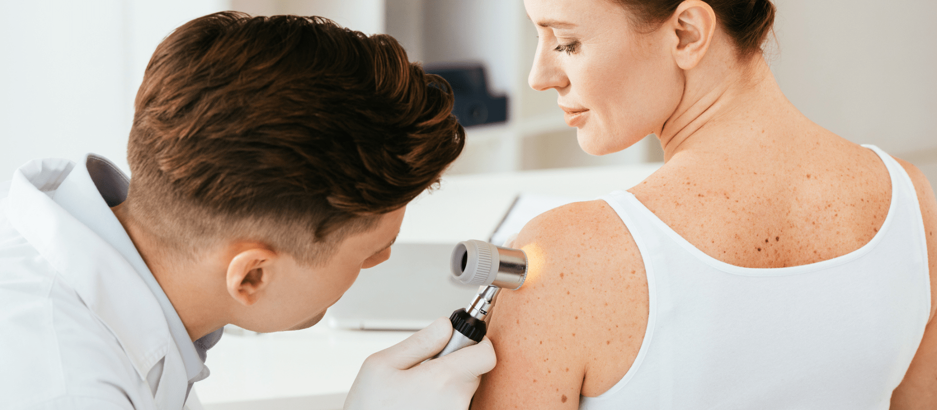 woman getting skin exam by doctor for left arm